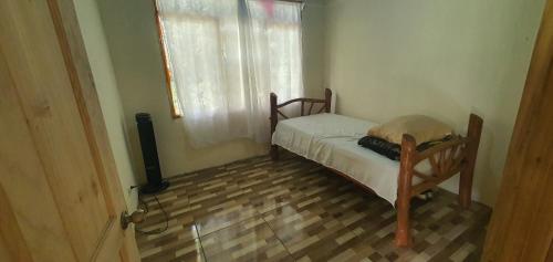 een kleine slaapkamer met een bed en een raam bij Options house in Bijagua