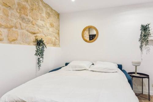 une chambre avec un lit blanc et un mur en pierre dans l'établissement Charmant studio Montorgueil, à Paris