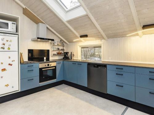 uma cozinha com armários azuis e um frigorífico branco em 4 person holiday home in Martofte em Martofte