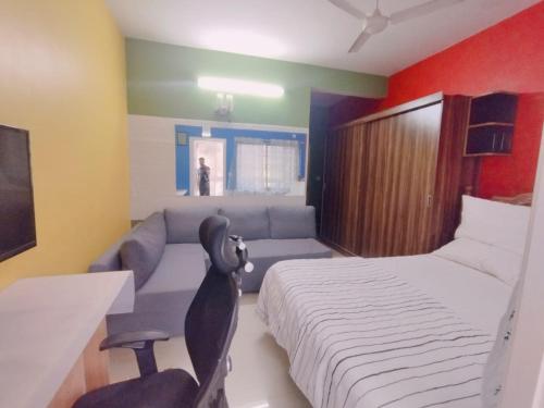 バンガロールにあるAmazistay offers Posh room for two with private balcony & bathroom & TV, Traveller, with shared Jacuzzi paid access near Brigade Senateのベッドとソファのあるホテルの部屋