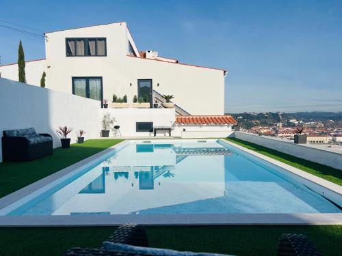 a villa with a swimming pool in front of a house at Vila Pombal Tomar Apartments - Pool & City Views in Tomar