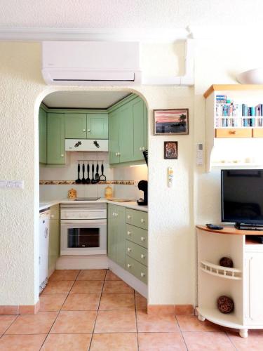 a kitchen with green cabinets and a tv at FIRST LINE Villa Floor Studio Apartment with amazing sea view Air Conditioned just 50m from the beach in Adeje
