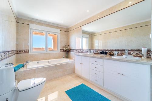a bathroom with two sinks and a tub and a toilet at Beachside villa with panoramic sea views in Benalmádena