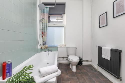 ein Bad mit einer Badewanne und einem WC in der Unterkunft Spacious and Comfy 4 Bed House, Free Parking, Wifi in Birkenhead