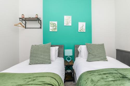 2 Betten in einem Zimmer mit blauer Wand in der Unterkunft Spacious and Comfy 4 Bed House, Free Parking, Wifi in Birkenhead