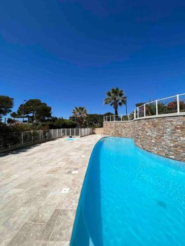 une piscine bleue avec un mur en pierre et des palmiers dans l'établissement Phare d'Agay - Zeezicht - 50 meter van het strand, à Saint-Raphaël