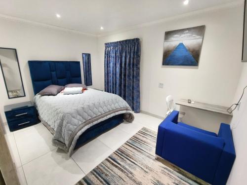 um quarto com uma cama azul e uma secretária azul em In Town Vaal em Vereeniging
