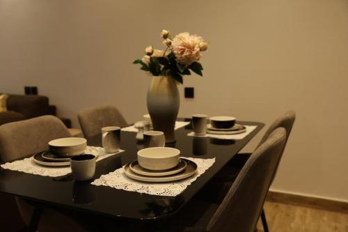 a table with cups and a vase with flowers on it at شاليه فراشة in Al Ahsa