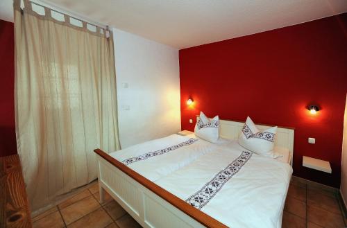 - une chambre avec un lit blanc et un mur rouge dans l'établissement KASTANIENHOF, à Burg