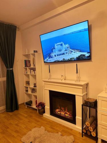 een woonkamer met een open haard en een flatscreen-tv erboven bij Vintage Apartament in Constanţa