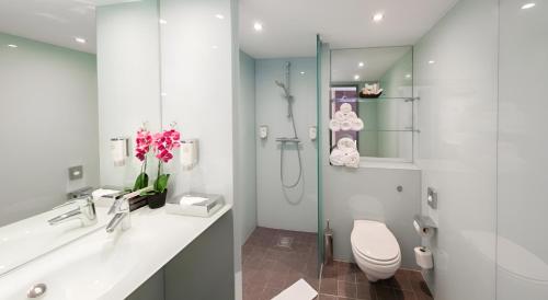 a white bathroom with a toilet and a shower at Hotel Orangerie in Vienna
