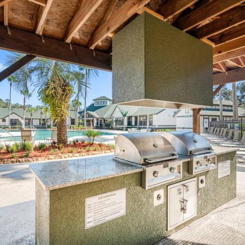 a outdoor kitchen with a grill in a resort at 4BD 2 MI to USF Free Pool + 24 Hour Gym in Tampa
