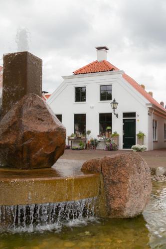 a building with a water fountain in front of a house at Appartement Badnieuweschans in Bad-Nieuweschans