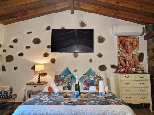 a bedroom with a bed with a tv on the wall at Romantic Casa Rural La Molinera in Santa Lucía