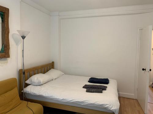 Covent Garden 2 Bed Apartment في لندن: غرفة نوم بسرير مع شراشف بيضاء ومصباح