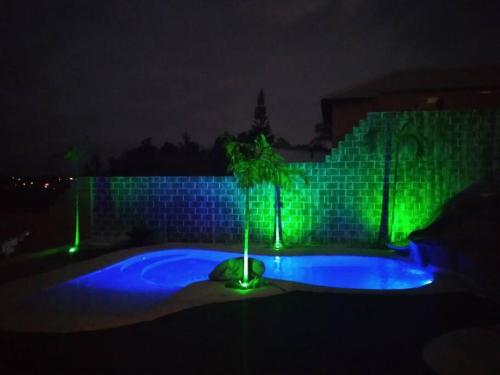 a night time picture of a pool with green lights at Rancho Saramago in Jundiaí