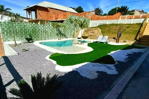 a backyard with a swimming pool and two chairs at Rancho Saramago in Jundiaí