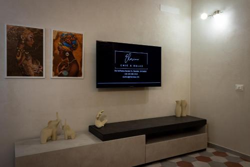 a room with a tv on a wall with a bench at Elorino Chic&Relax in Rosolini