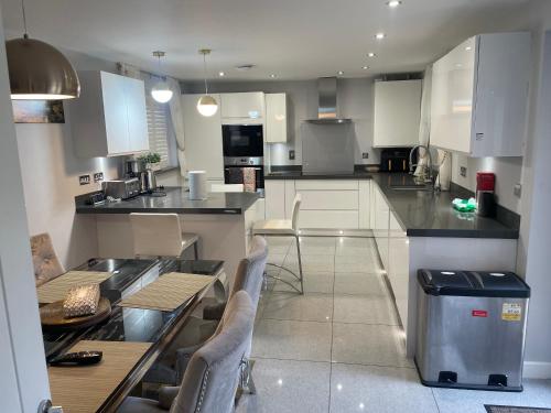 a kitchen with white cabinets and a table and chairs at Luxurious Five-Bedroom Haven in Long Stanton