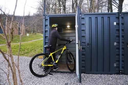 un homme tient un vélo dans un garage dans l'établissement Domki Karpatia BB, à Bielsko-Biała