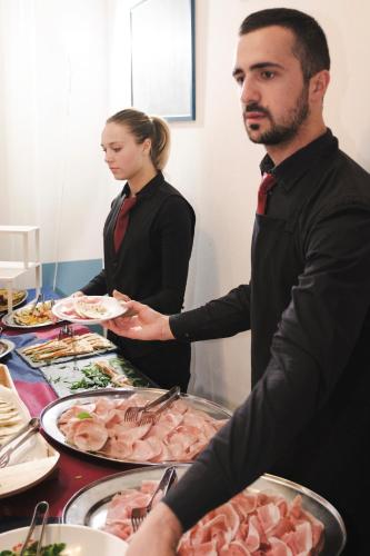 a man and a woman preparing food at a buffet at Hotel Cheri in Rimini