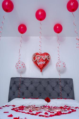 un cœur suspendu sur un mur au-dessus d'un lit avec des ballons rouges dans l'établissement Posada La Rosa, à Santa Ana