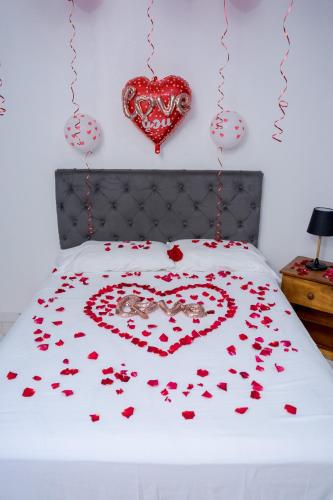 Una cama con un corazón hecho de corazones rojos en Posada La Rosa en Santa Ana