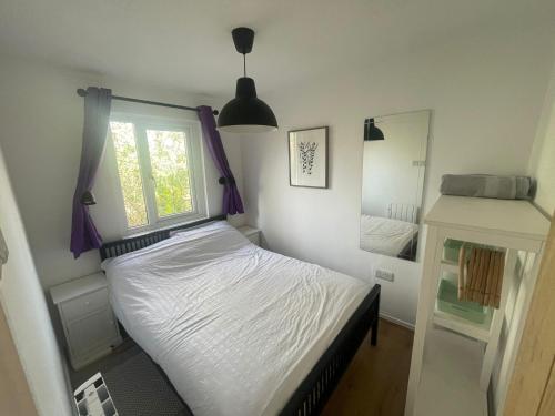 a bedroom with a bed with purple curtains and a window at Woodland bungalow, fantastic location in Uny Lelant