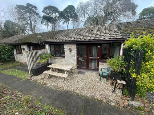 a small house with a picnic table and a bench at Woodland bungalow, fantastic location in Uny Lelant