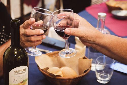 two people holding glasses of wine next to a basket of bread at Hotel Cheri in Rimini