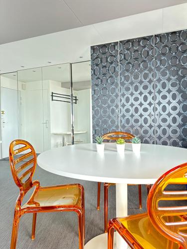 une salle à manger avec une table et des chaises blanches dans l'établissement T2 La vue panoramique sur l'océan à 180, à Saint-Jean-de-Monts