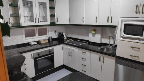 a kitchen with white cabinets and a sink and a microwave at Dúplex San Lorenzo 2 PARKING GRATUITOS in Jaén