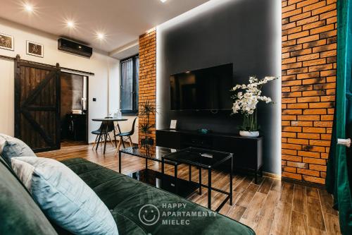 een woonkamer met een bank en een flatscreen-tv bij Happy Nest - Happy Apartamenty Mielec in Mielec