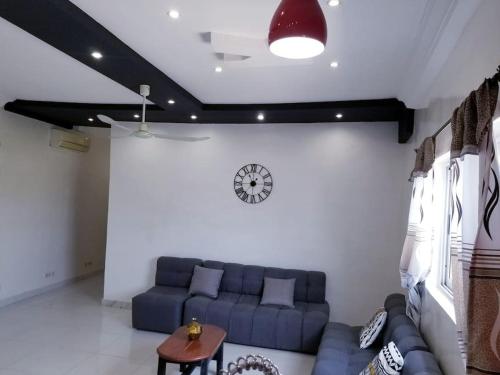 a living room with a blue couch and a clock on the wall at Appartement moderne K WhiteRed à pk10, Cotonou in Cotonou
