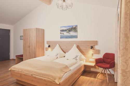 ein Schlafzimmer mit einem Bett und einem roten Stuhl in der Unterkunft Landgasthaus Zollerstuben in Bermatingen