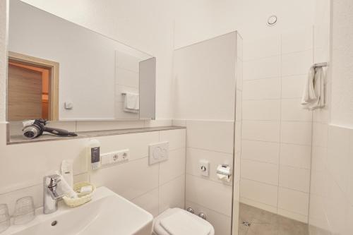 a white bathroom with a toilet and a sink at Landgasthaus Zollerstuben in Bermatingen