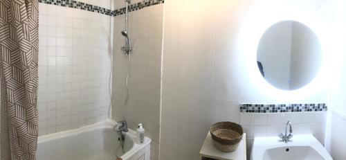 uma casa de banho com uma banheira, um lavatório e um espelho. em Appartement Saint-Malo Centre - Arrivée autonome em Saint Malo