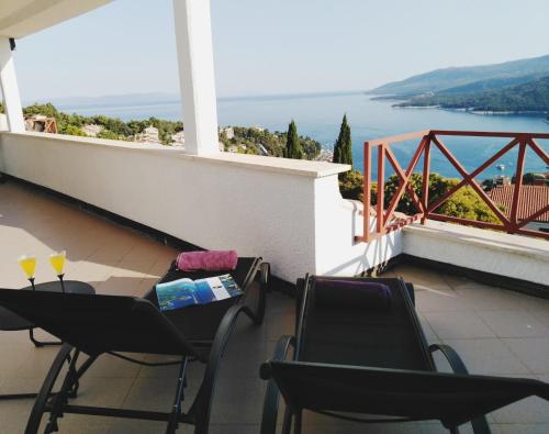 een balkon met stoelen en een tafel met wijnglazen bij Sea View K Loft in Rabac