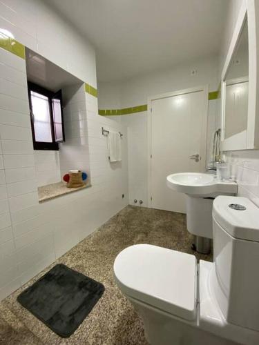a white bathroom with a toilet and a sink at Casa Bamiak in Vilagarcia de Arousa