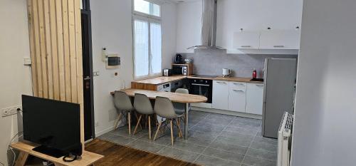 a kitchen with a wooden table and chairs in it at Maison Cosy in Lourdes