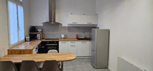 eine Küche mit Holztisch und Kühlschrank in der Unterkunft Maison Cosy in Lourdes