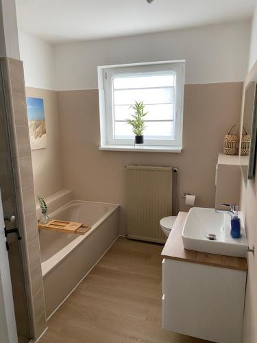 baño con bañera, lavabo y ventana en Gemütliches Ferienhaus in Küstennähe, en Wilhelmshaven