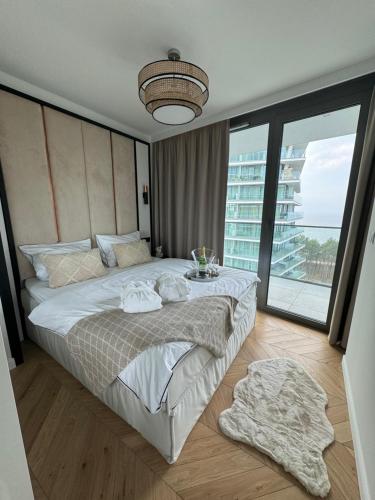 a bedroom with a large bed and a large window at Luxury Apartment Tyballtic 7th Floor in Międzyzdroje
