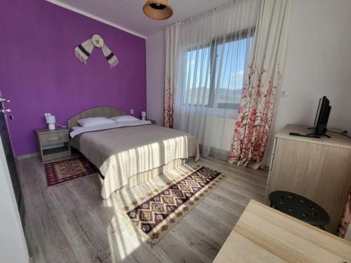 a bedroom with a bed with purple walls and a window at Agropensiunea Pe Poderei in Cupşeni