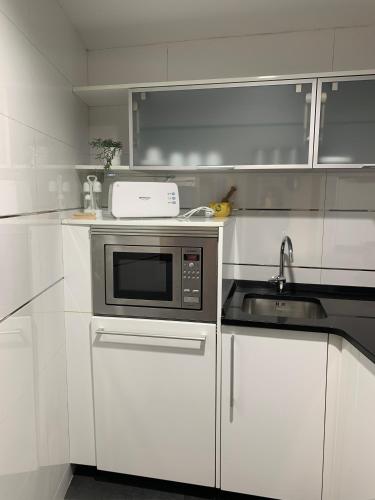 a white kitchen with a microwave and a sink at Apartament l'Empalme d'Àger in Ager