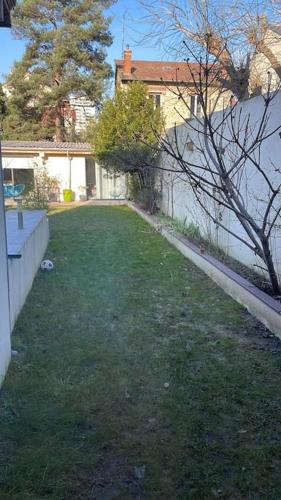 une cour avec une clôture et une cour avec de l'herbe verte dans l'établissement Studio proche sites JO, à Colombes