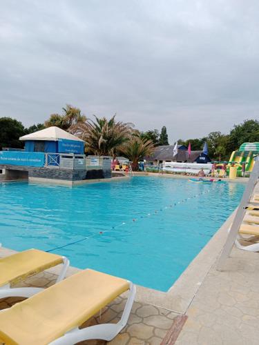 une grande piscine avec de l'eau bleue et des chaises jaunes dans l'établissement Domaine de Kerlann, à Pont-Aven