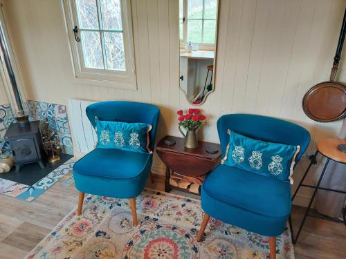 two blue chairs in a room with a table at The Humble Hut in Wooler