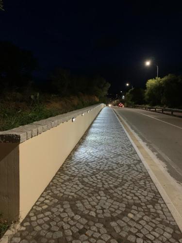an empty road at night with a wall on the side at Su Giardinu in Girasole