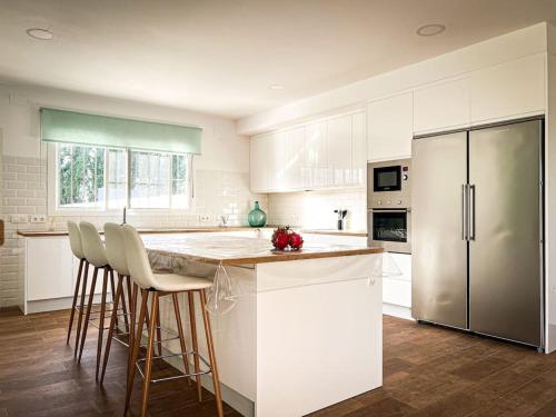 a kitchen with white cabinets and a island with bar stools at Casa rural , campo ocio, eventos, Villa Rural in Dos Hermanas